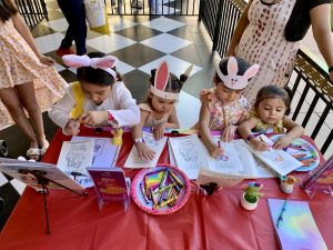 Miss Fairy G handing out coloring books to happy children while entertaining families.